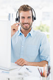 Portrait of a casual young man with headset using computer
