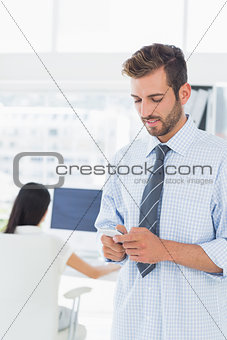 Male artist text messaging with colleague in background