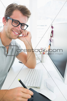 Side view of a casual male photo editor using graphics tablet