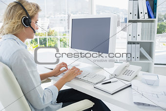 Casual young woman with headset using computer