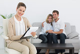 Financial adviser writing notes with couple in background
