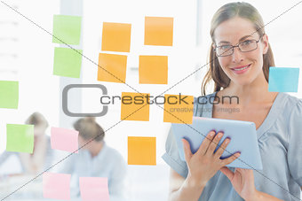 Smiling female artist with digital tablet and colorful sticky notes
