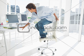 Young man standing over chair in bright office