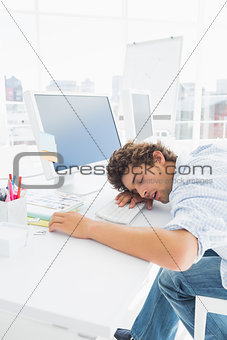 Casual businessman with head over keyboard at desk