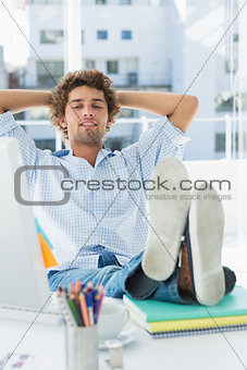 Casual young man with legs on desk in bright office