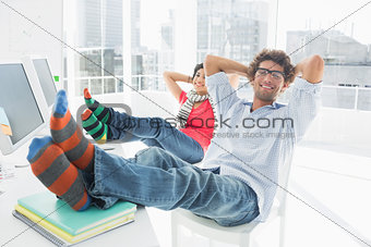Relaxed casual couple with legs on desk in office