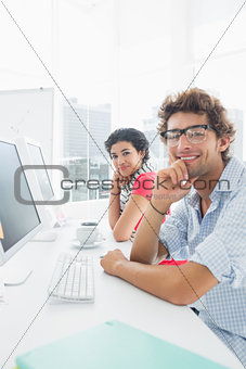 Smiling casual couple sitting at desk in office