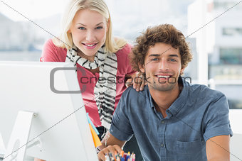 Smiling casual couple using computer in bright office