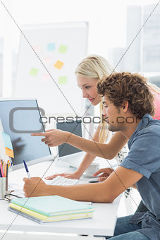 Casual couple using computer in office