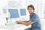 Smiling casual young man using computer in office