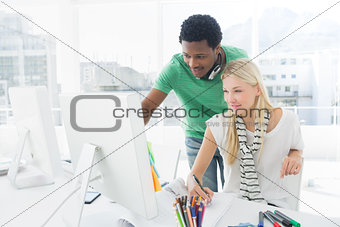 Artist drawing something on paper with colleague at office