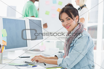 Portrait of an artist using computer with colleagues behind