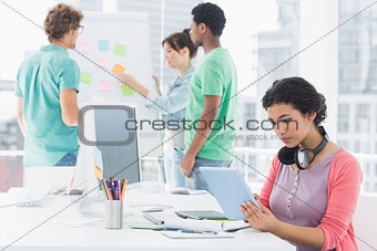 Woman using digital tablet with group of colleagues behind