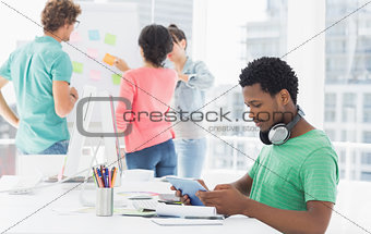 Casual man using digital tablet with colleagues behind in office