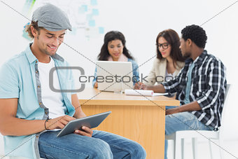 Man using digital tablet with colleagues behind in office