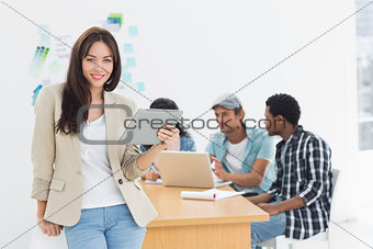Woman using digital tablet with colleagues behind in office