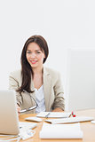 Well dressed woman with laptop at desk in office