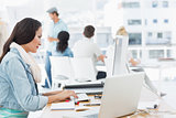 Woman using computer with colleagues behind in office
