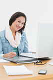Smiling casual woman with catalog in front of computer in office
