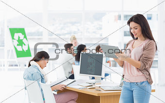 Artist using digital tablet with colleagues in at office
