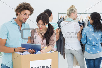 People with clothes donation while using digital tablet