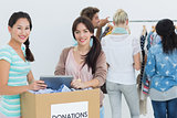 People with clothes donation while using digital tablet