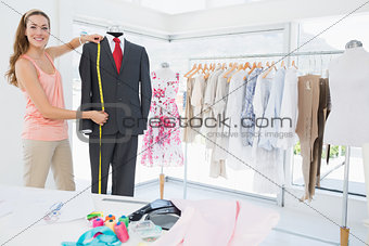 Female fashion designer measuring suit on dummy