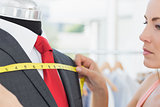 Closeup of a female fashion designer measuring suit on dummy