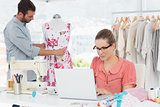 Woman using laptop with fashion designer working at studio