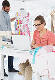 Woman using laptop with fashion designer working at studio