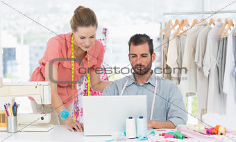 Fashion designers using laptop in bright studio