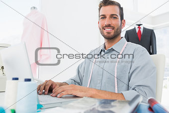 Smiling male fashion designer using laptop in studio