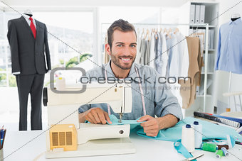 Smiling male tailor sewing in workshop