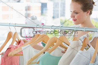 Smiling female customer at clothing rack in store