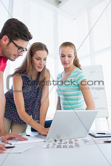 Casual business people using laptop in office