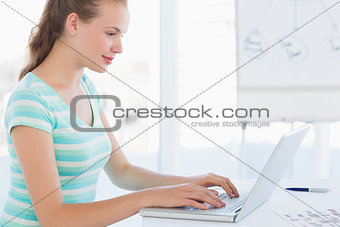 Young casual woman using laptop at office