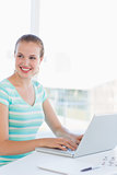 Young casual woman using laptop at a bright office