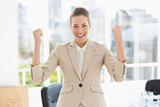 Cheerful businesswoman clenching fists in office