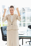 Cheerful businesswoman clenching fists in office
