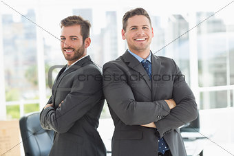 Businessmen standing with arms crossed in office