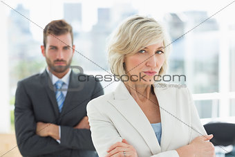 Mature businesswoman and young man with arms crossed