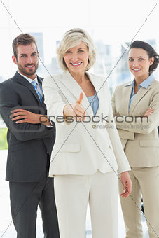 Confident businesswoman offering handshake with team in office