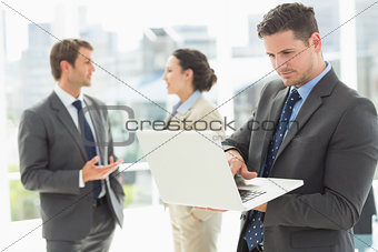 Businessman using laptop with colleagues discussing in office