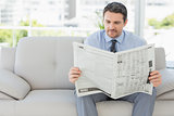 Well dressed man reading newspaper at home