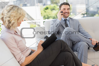 Businessman on call and secretary with diary at home