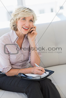 Female secretary with diary while using mobile phone