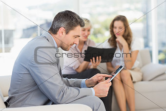 Businessman using digital tablet with colleagues behind