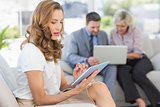 Businesswoman using digital tablet with colleagues using laptop behind