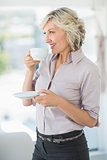 Smiling beautiful businesswoman drinking tea in office