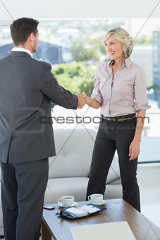 Executives shaking hands over a coffee table at home